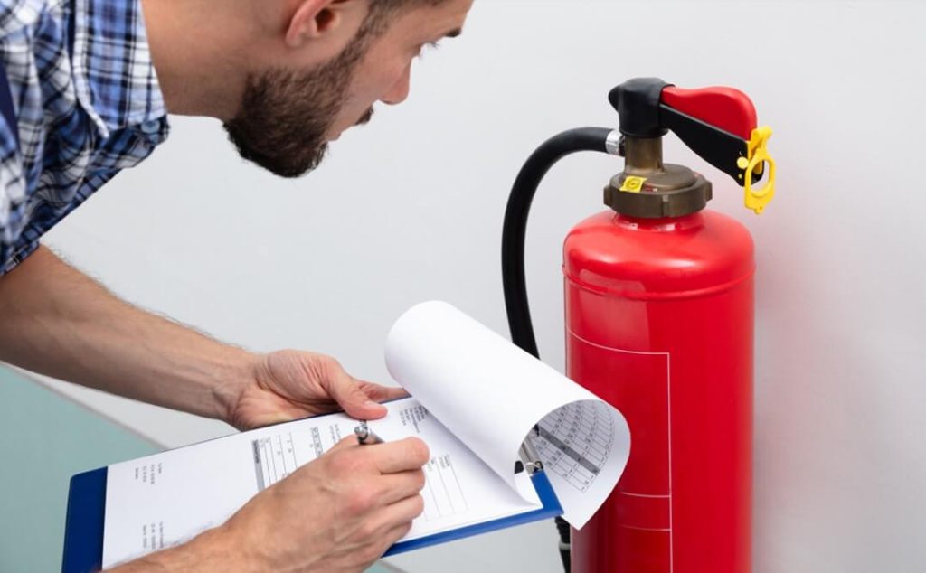 man inspecting fire extinguisher